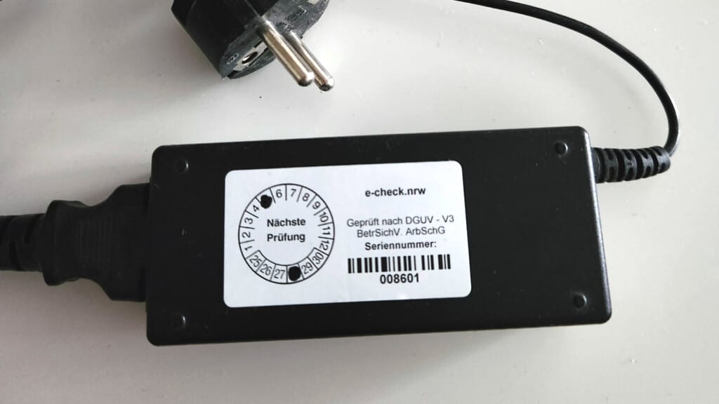 e-check.nrw – Ein Netzteil mit dem Aufkleber von e-check.nrw zur bestandenen DGUV V3 Prüfung