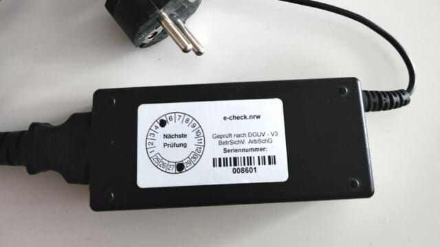 e-check.nrw – Ein Netzteil mit dem Aufkleber von e-check.nrw zur bestandenen DGUV V3 Prüfung