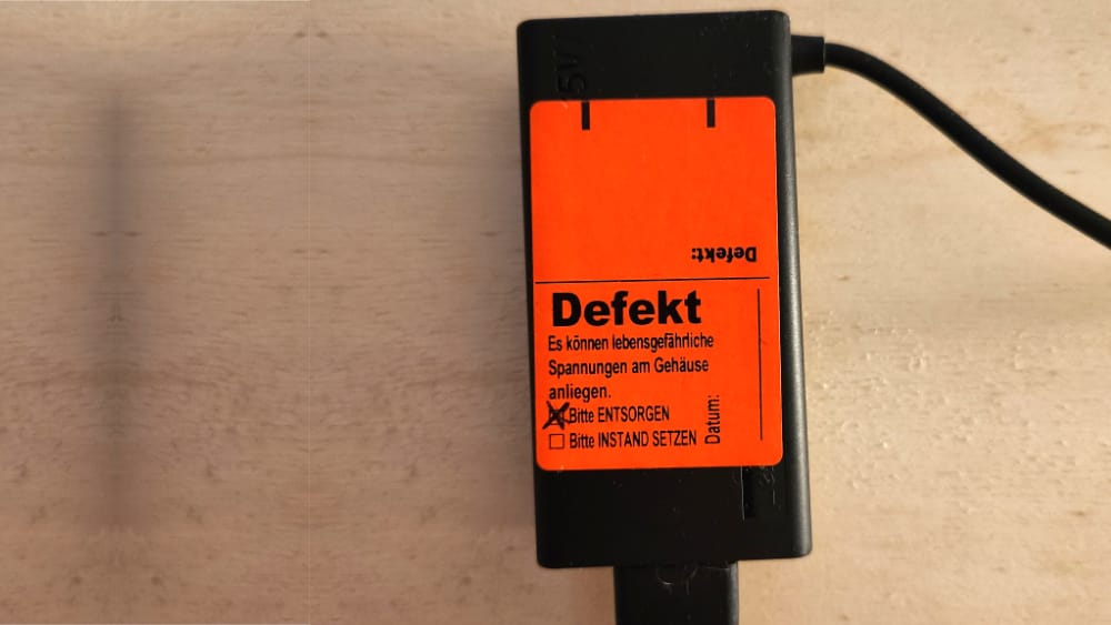 e-check.nrw – Ein Netzteil mit dem roten Aufkleber von e-check.nrw bei nicht bestandener DGUV V3 Prüfung